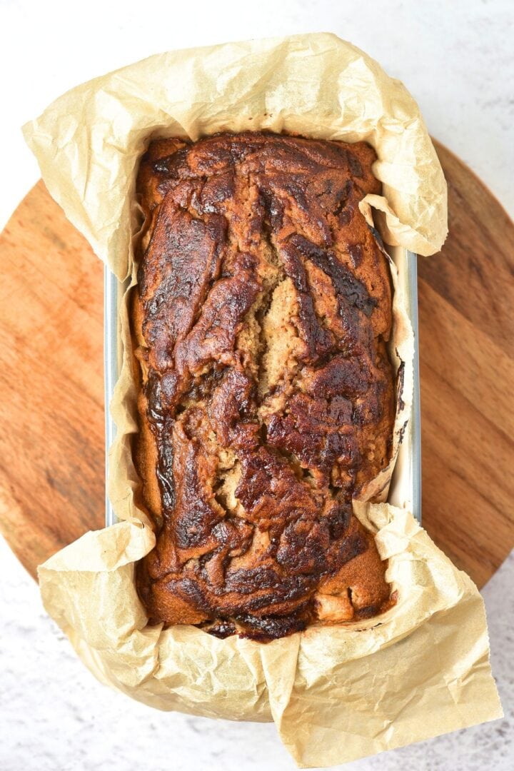 Freshly baked apple butter loaf in parchment-lined loaf pan.