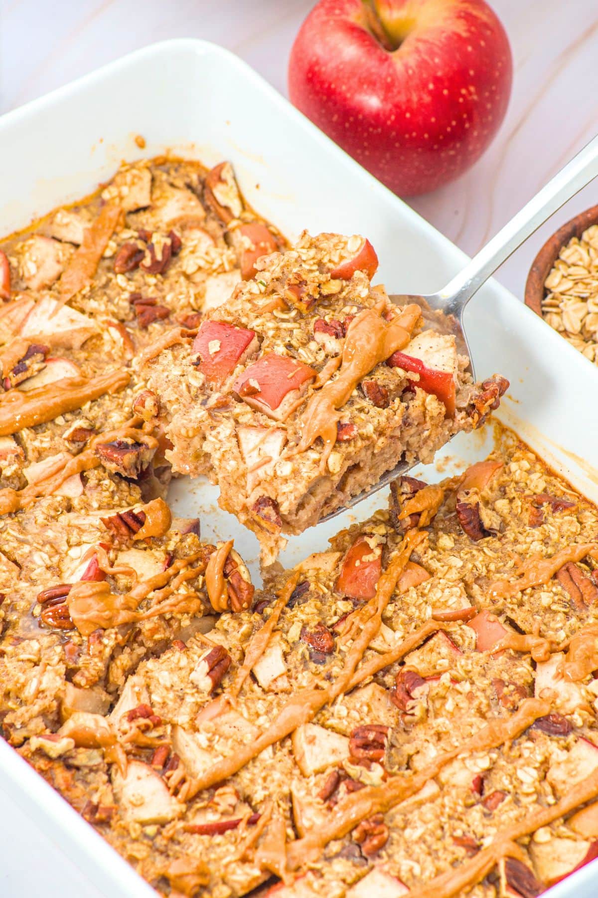 Apple Cinnamon Baked Oatmeal (Gluten-Free, Dairy-Free) Holding up spoonful of baked oatmeal from baking dish