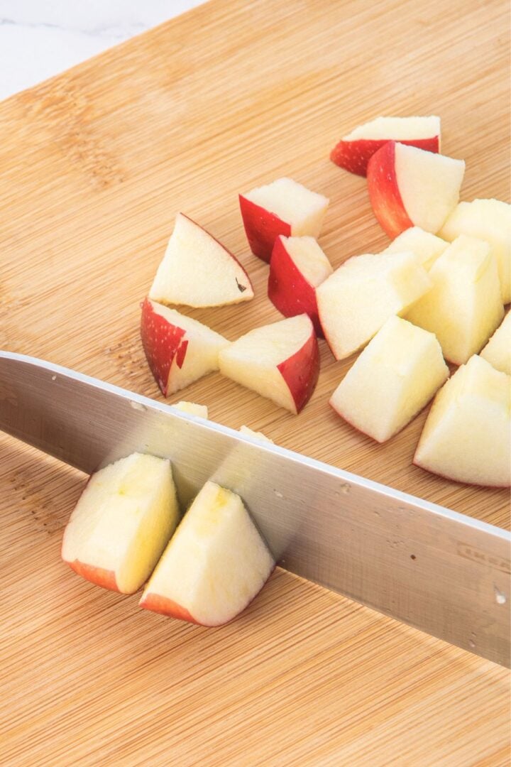 Cutting apples into small cubes on wooden board