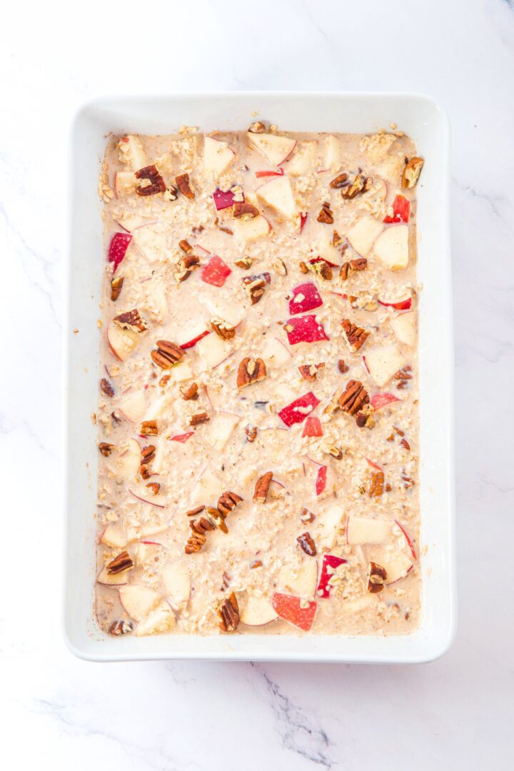A casserole dish with mixture of oats, cubed apples, chopped pecans