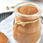 A jar of apple pie spice on parchment paper.