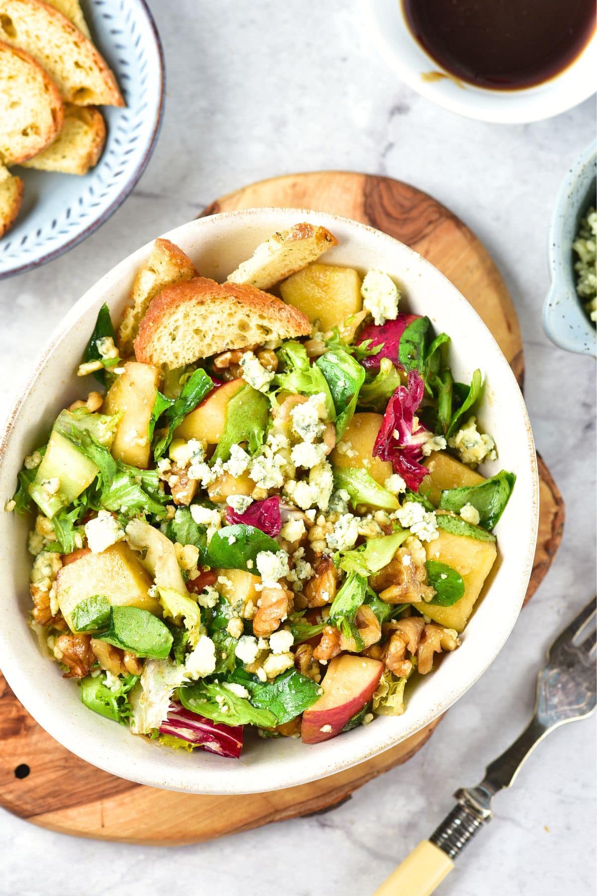 Top down view of apple walnut and blue cheese salad on wooden board