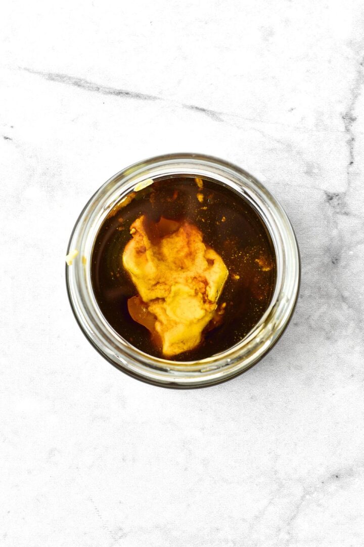 Top down view of balsamic vinegar and mustard dressing in small bowl.