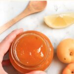 Hand holding jar of apricot jam