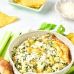 A bowl of artichoke spinach dip with vegetable crudités