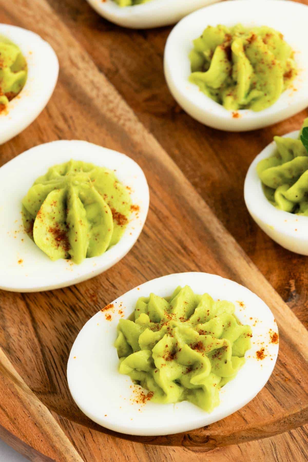 Top down view of deviled eggs on wooden board.