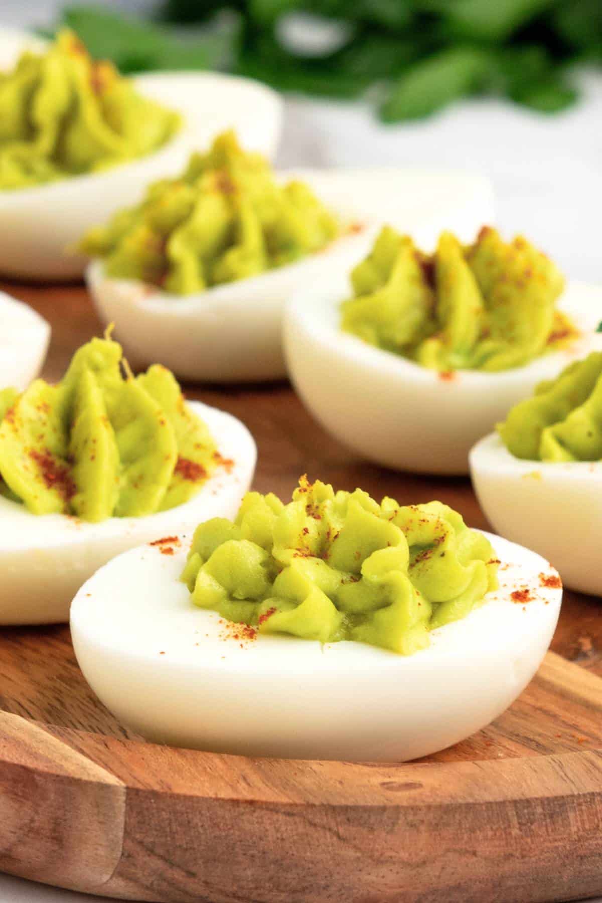 Up close shot of avocado deviled eggs on wooden board.