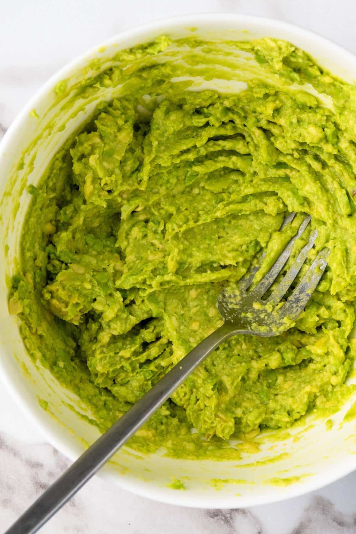 Mashing avocado with a fork in a bowl.