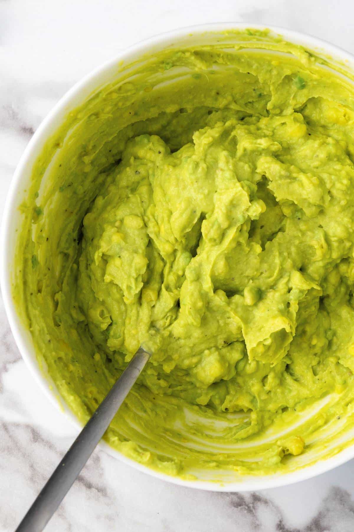 Mixing avocado egg yolk filling in bowl.