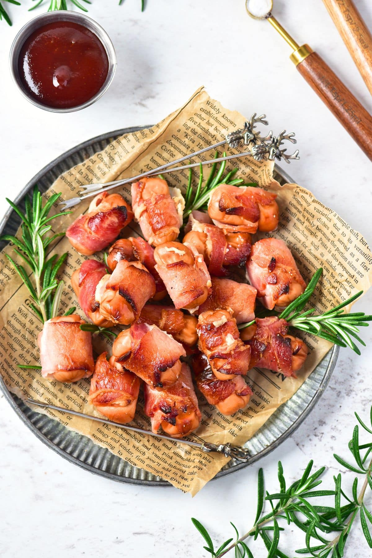 Top down view of plate of bacon-wrapped little smokies and rosemary sprigs.