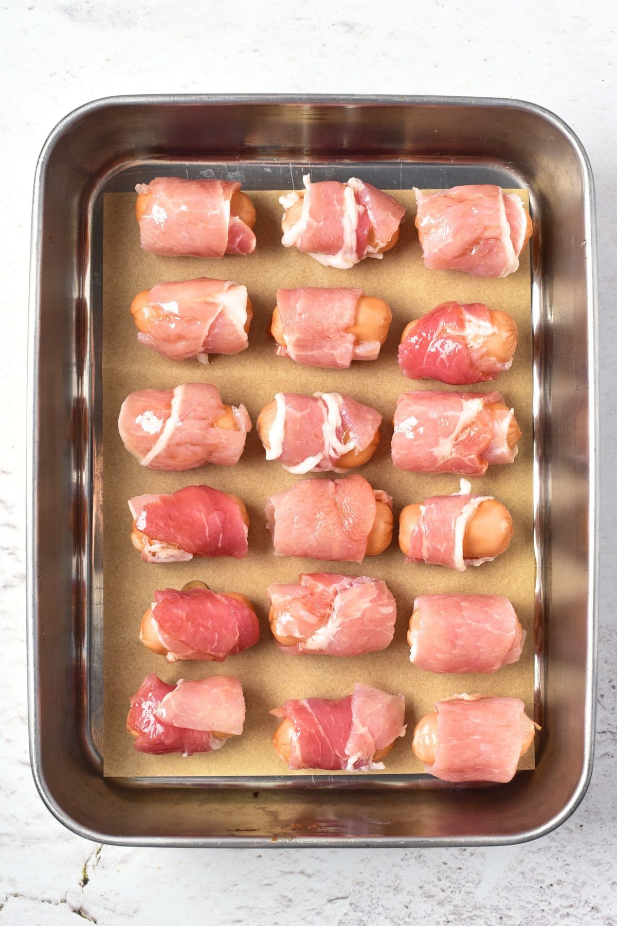 Little smokies wrapped in bacon on parchment-lined baking sheet