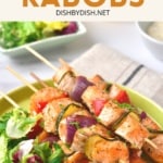 Salmon skewers and salad greens on a round plate.