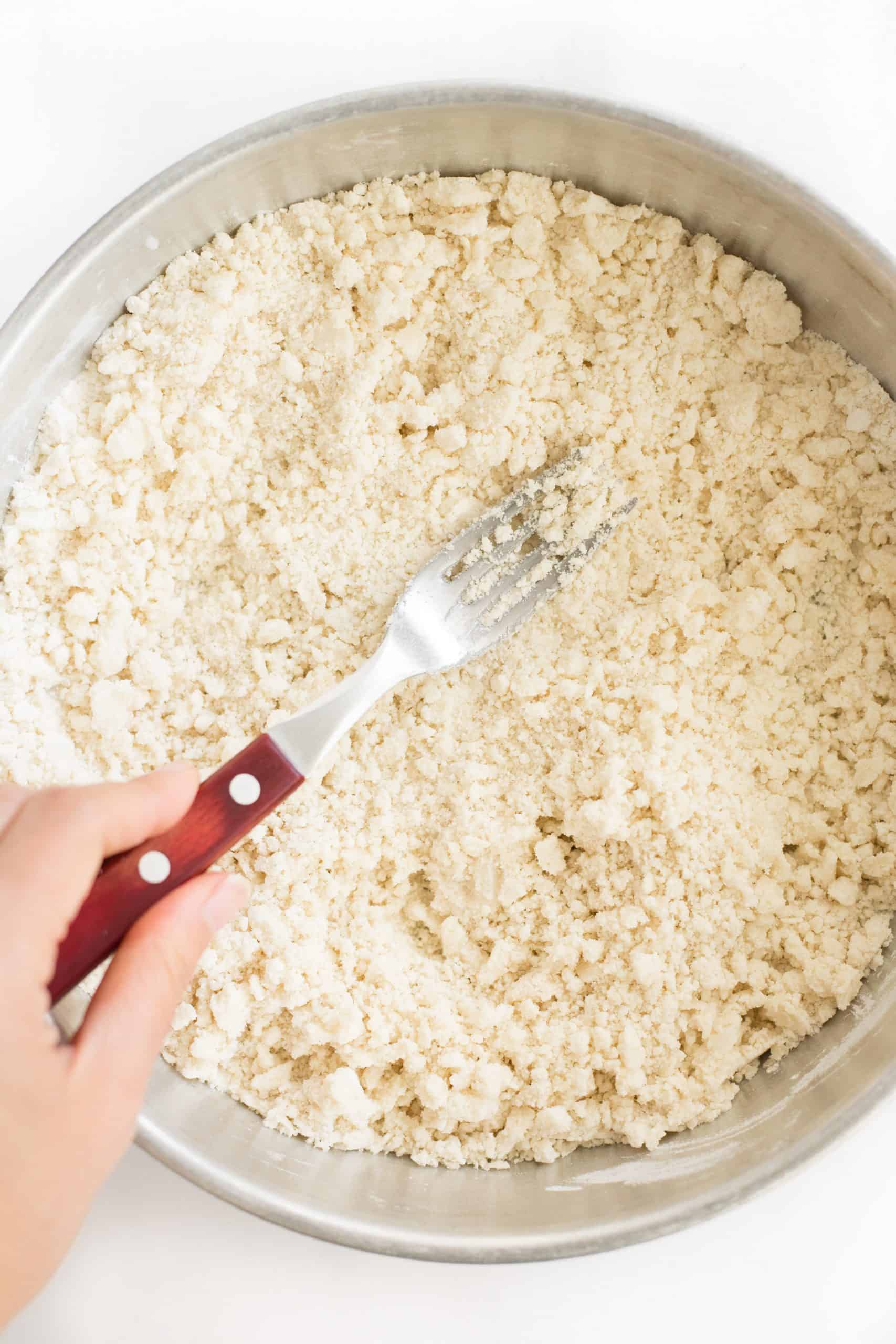 Using a fork to cut the chilled coconut oil into the flour.