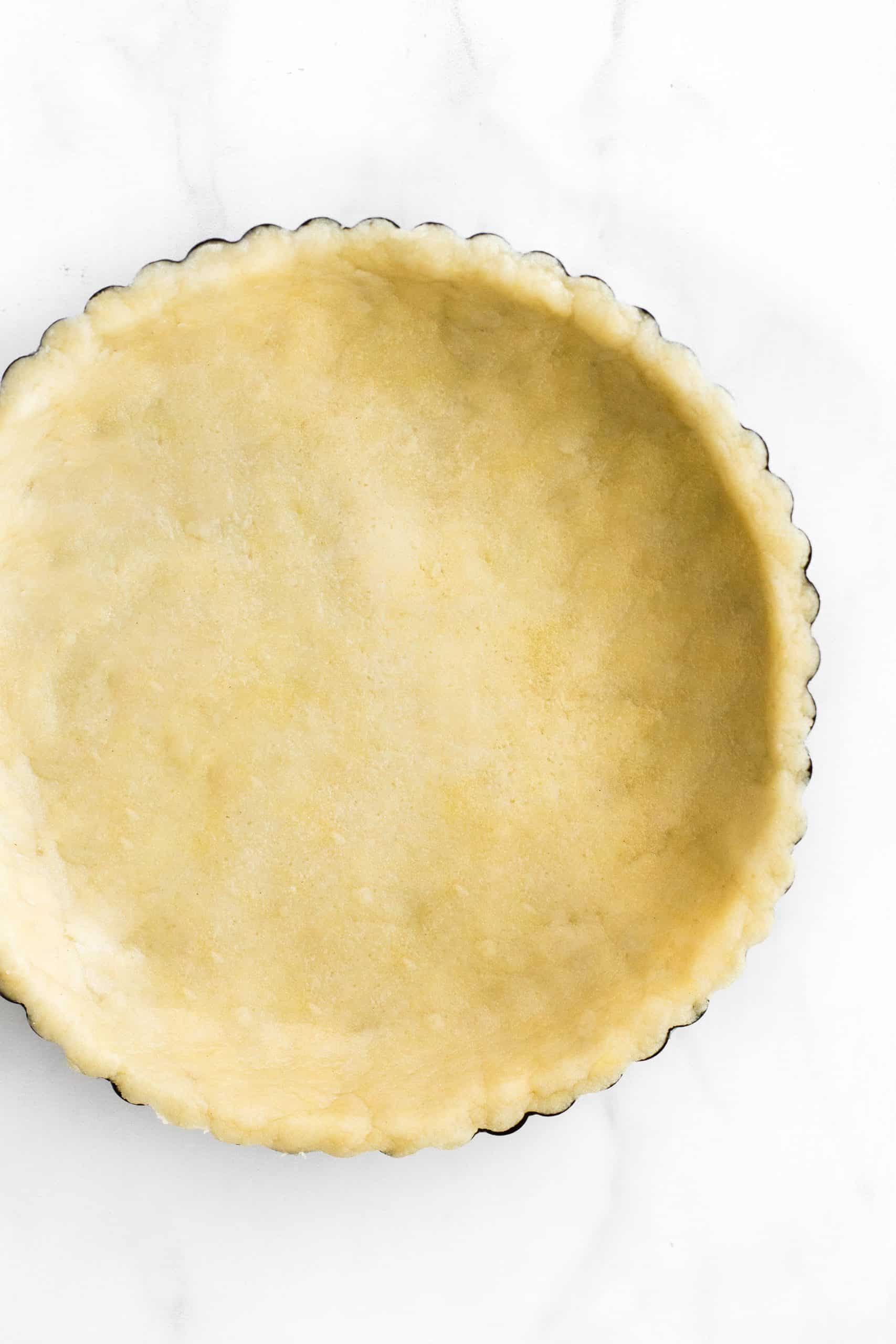 Gluten-free dairy-free pie crust dough pressed into a metal tin pan.