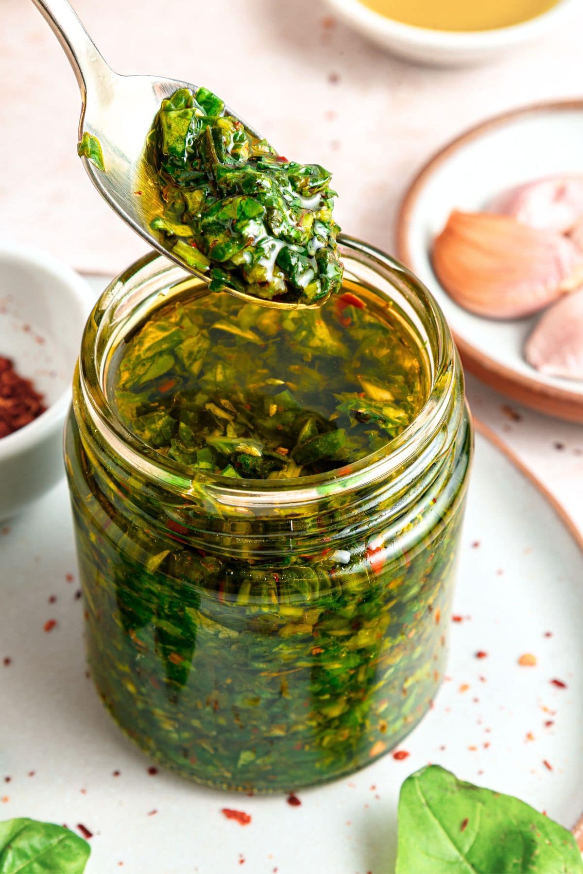 Holding up a spoonful of argentinian chimichurri with basil from a jar