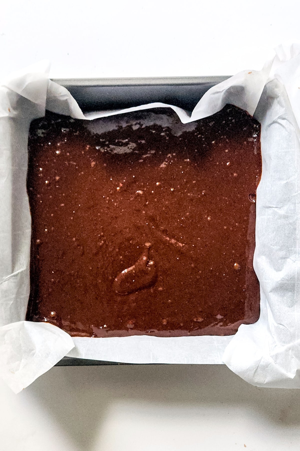 Brownie batter in parchment lined pan.