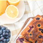Top down view of loaf of blueberry almond bread with blueberries and lemon