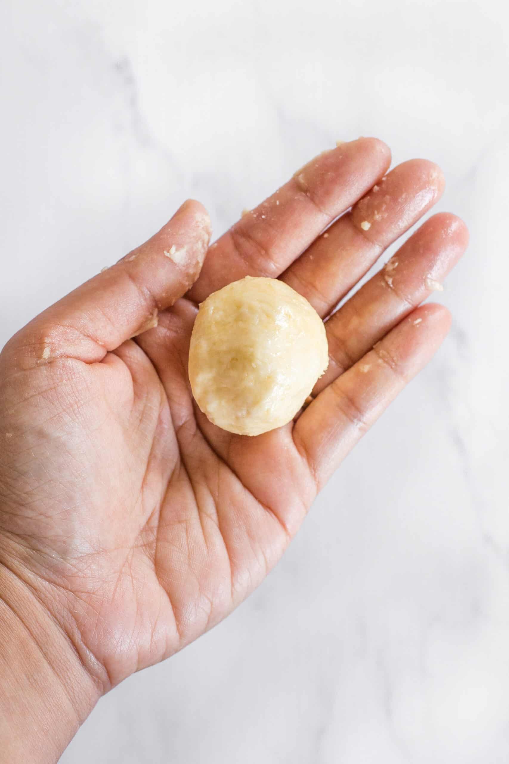 A hand holding a dough ball.