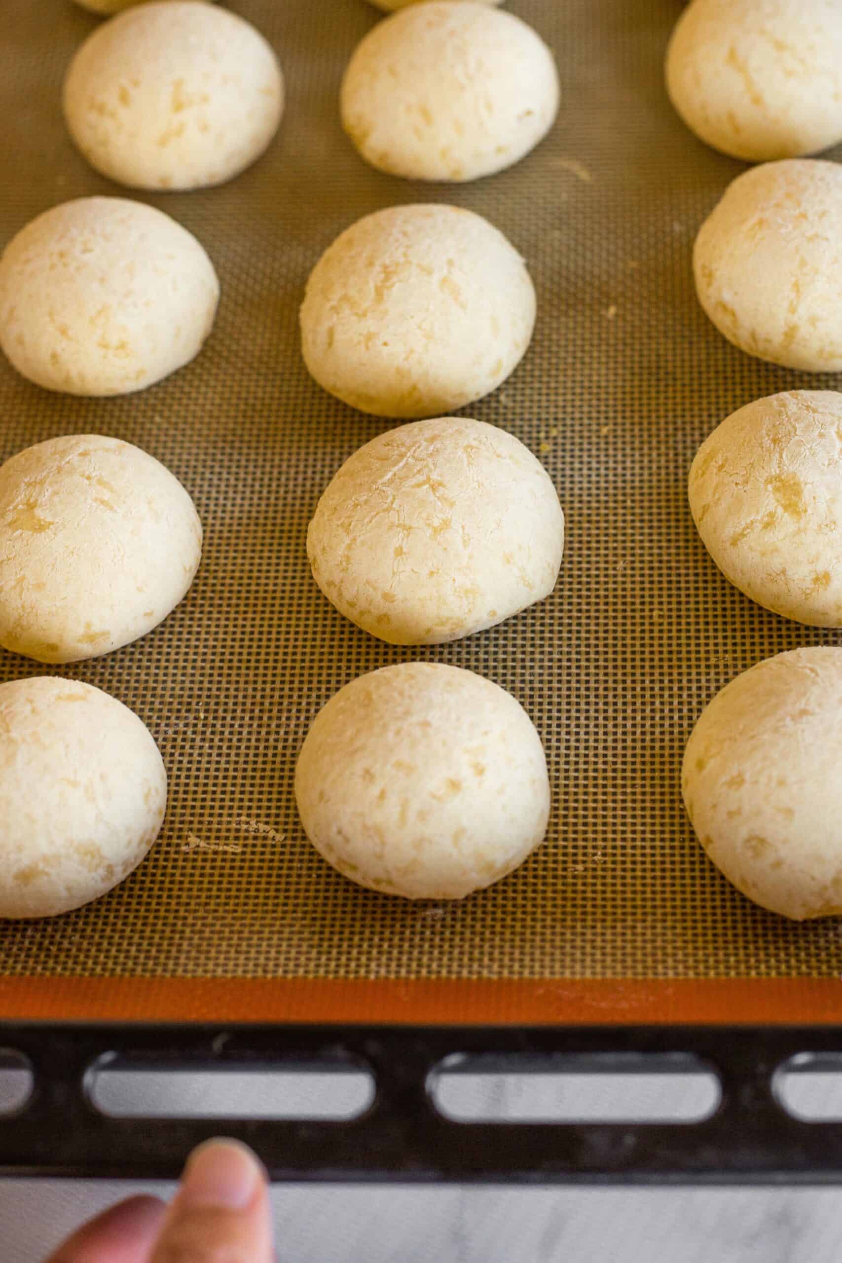 Freshly baked Brazilian cheese bread on a silpat-lined baking sheet.