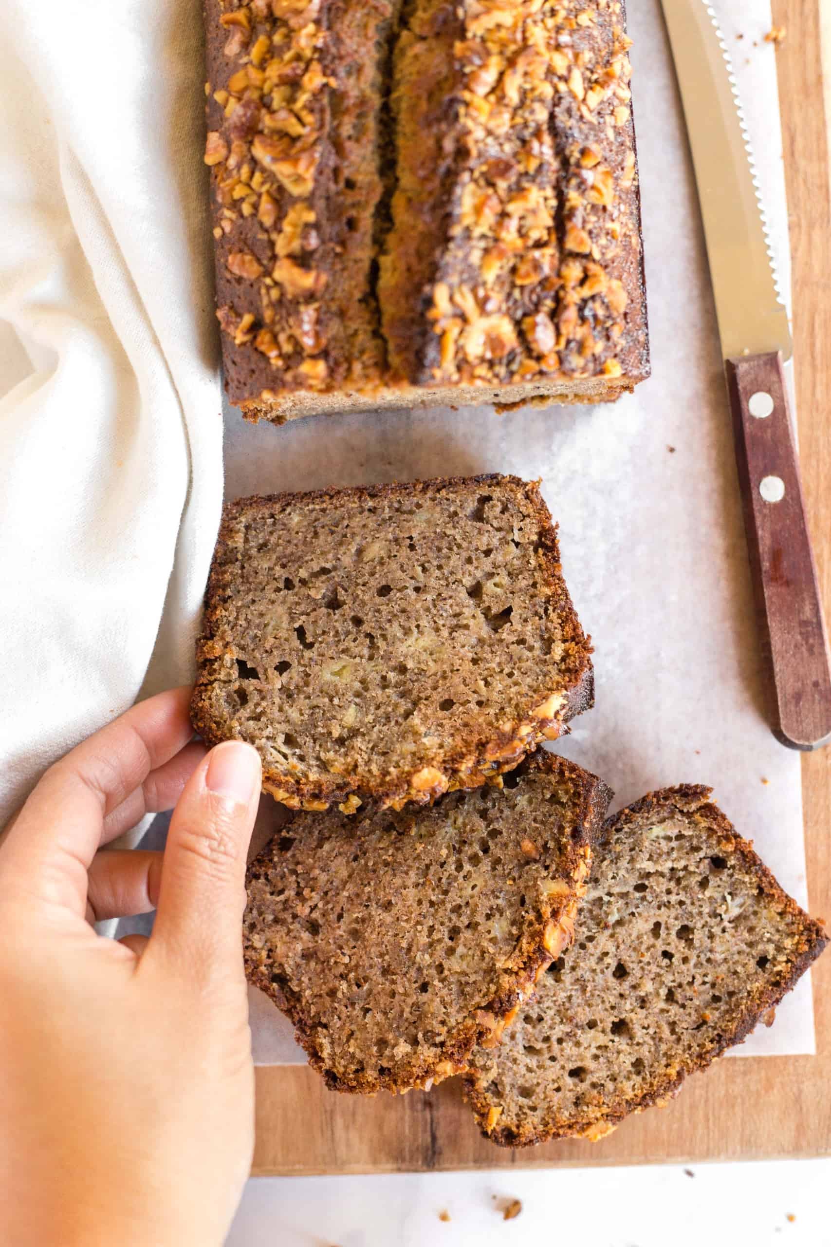 Reaching for a slice of buckwheat banana bread on parchment paper.