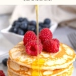 Pouring maple syrup over a stack of pancakes.