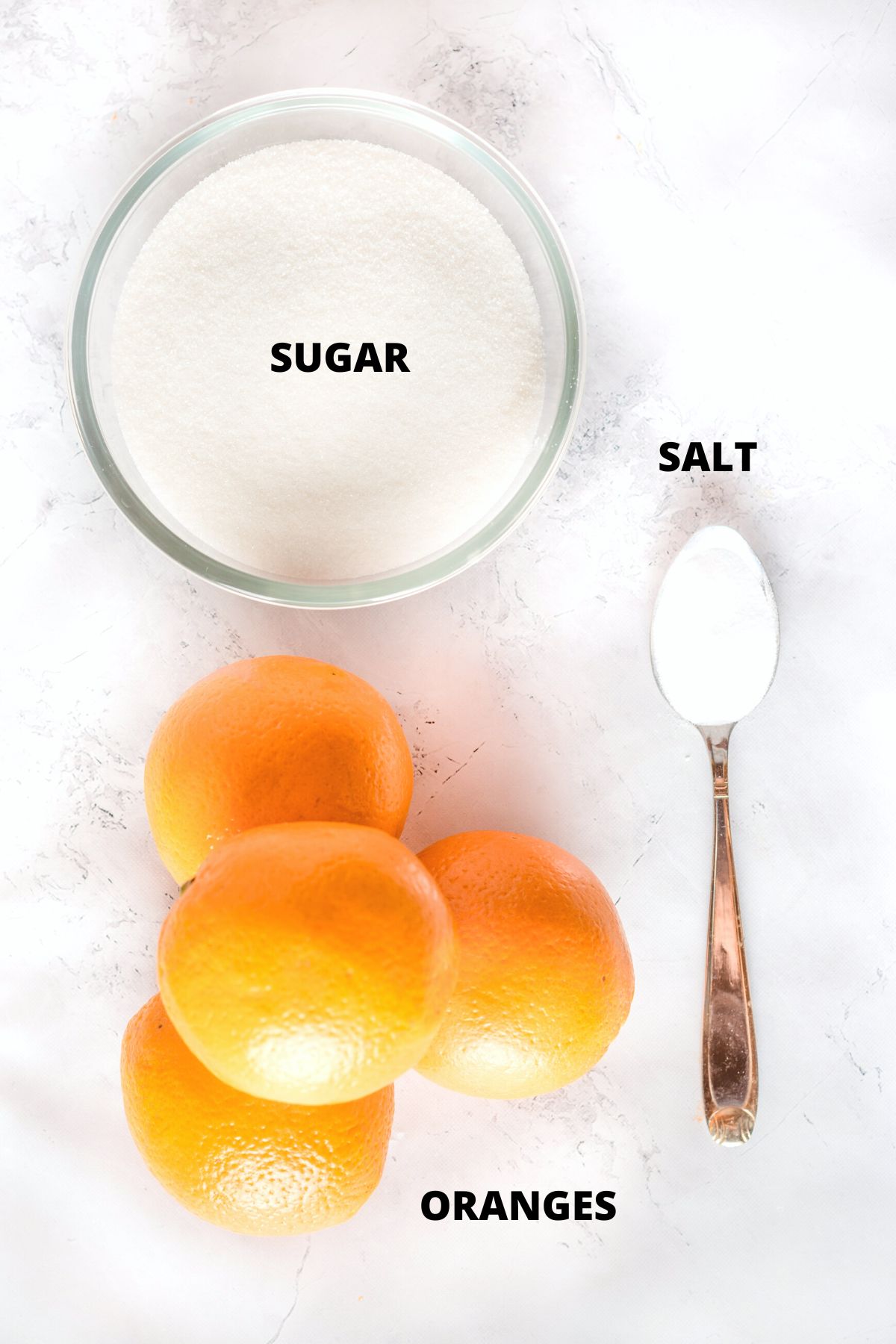 Ingredients for candied orange peel recipe laid out on marble board.