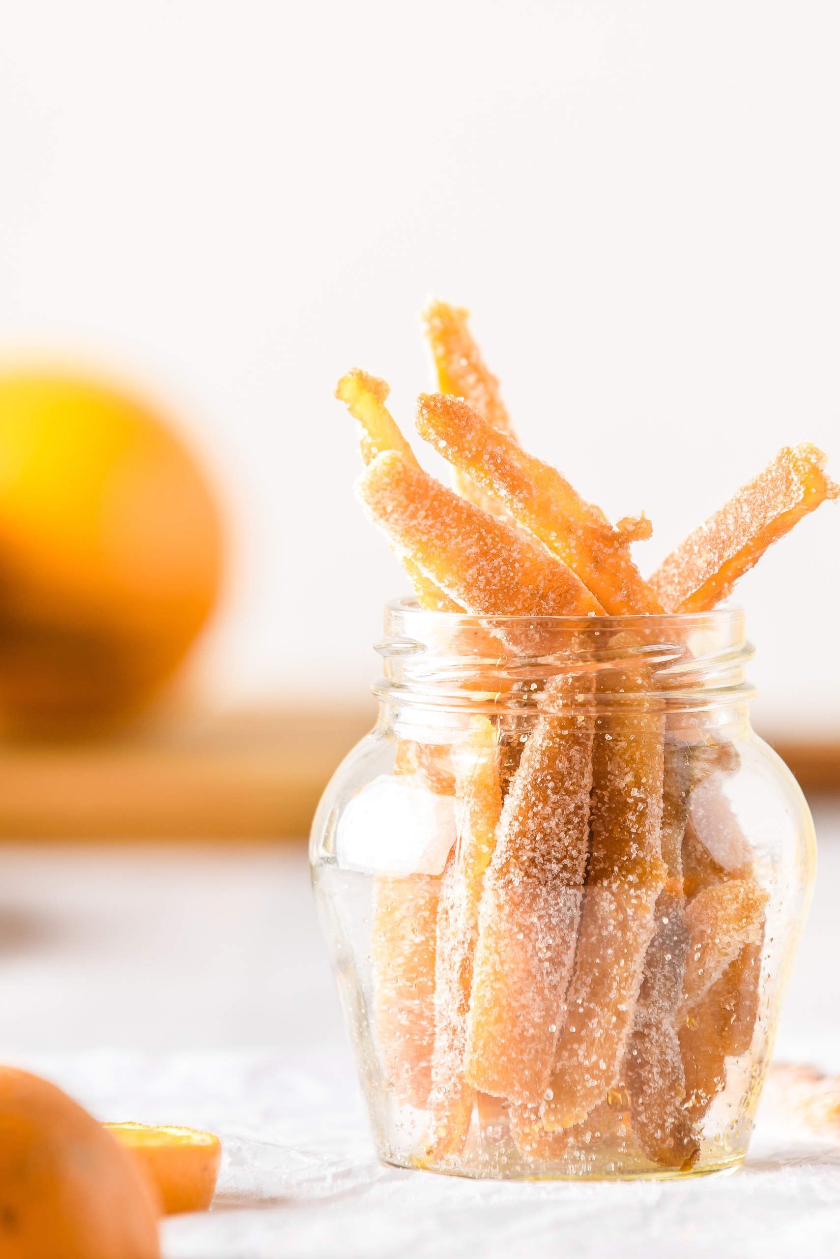 Homemade candied orange peels in a glass jar.