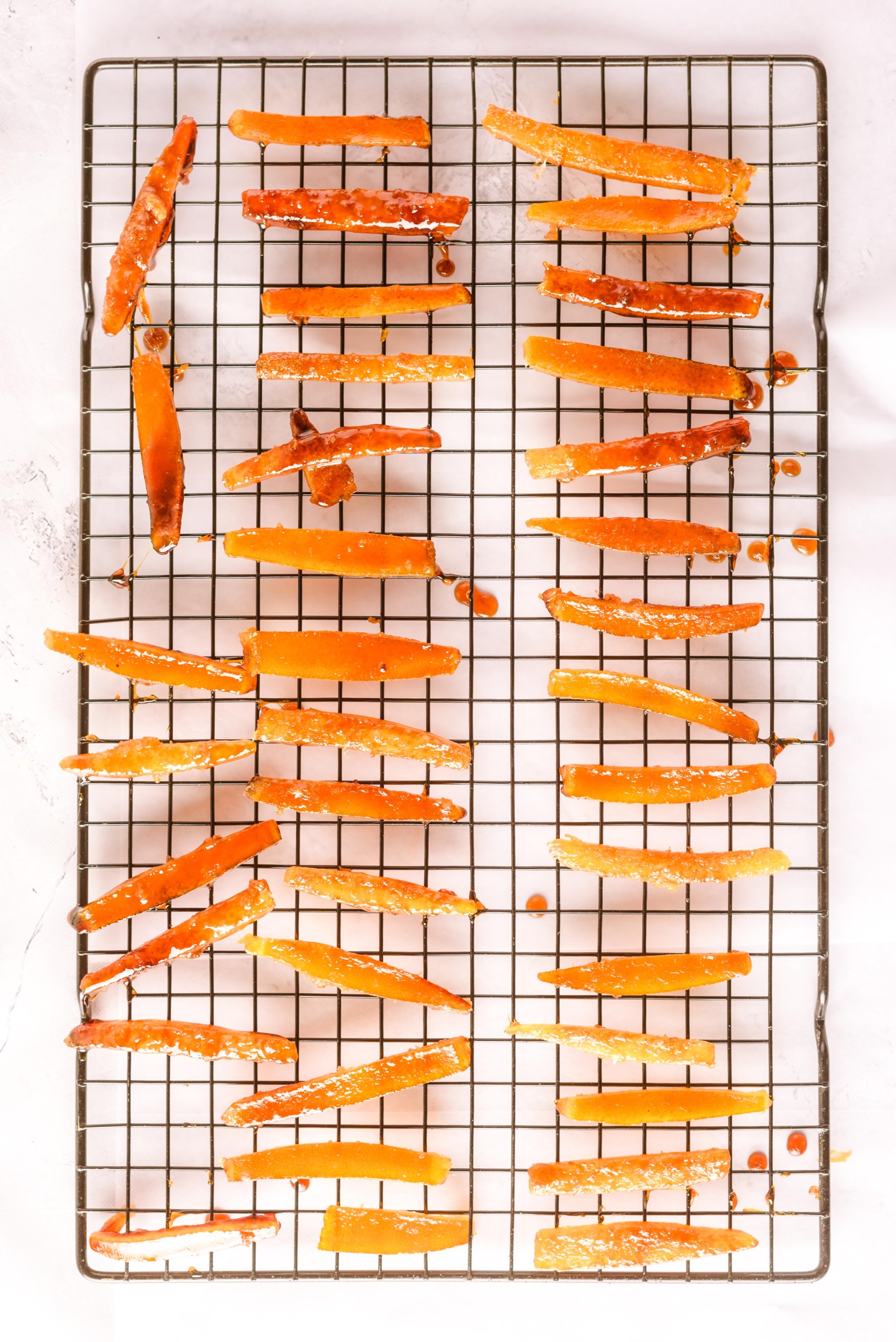 Syrup-coated orange peels cooling on a wire rack.