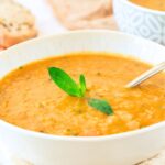 A bowl of carrot lentil soup topped with fresh mint
