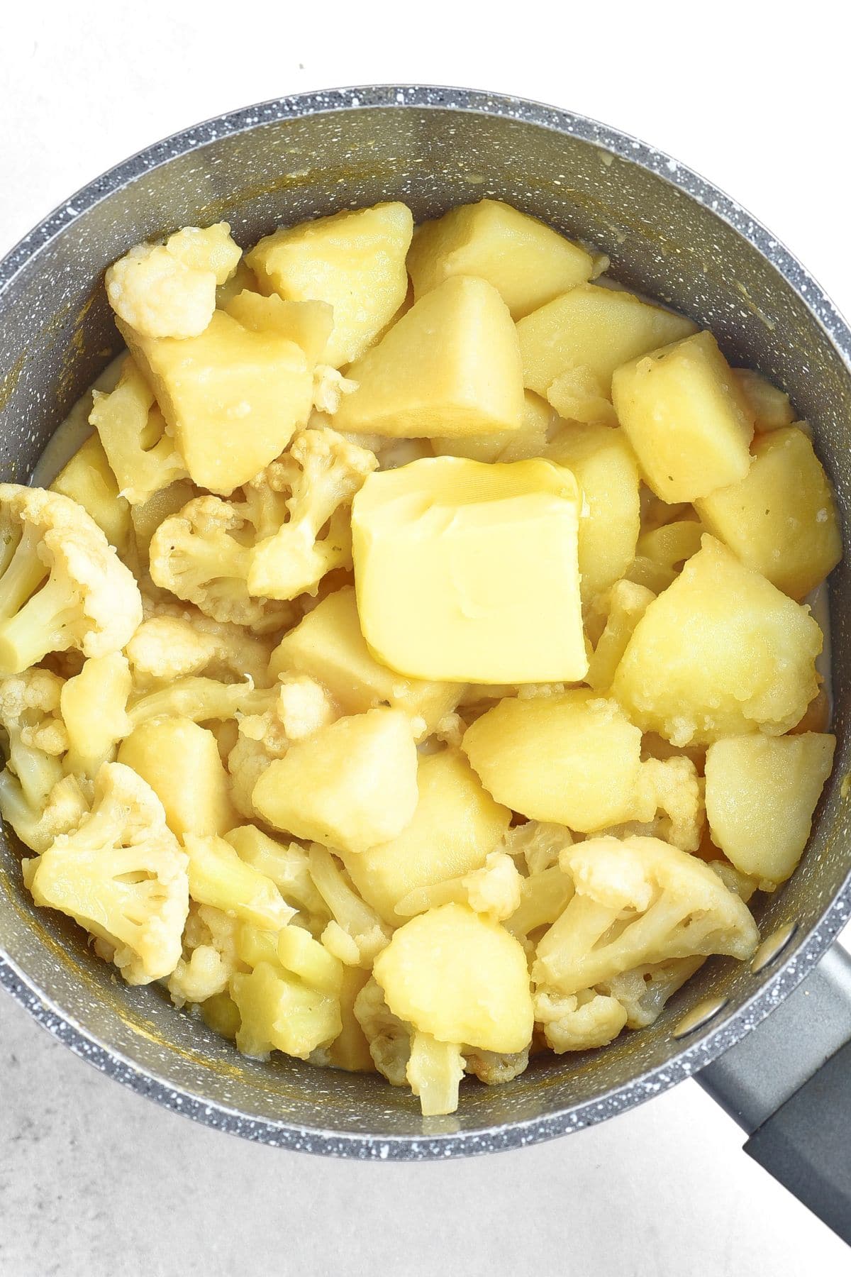 A pot of cooked cauliflower florets and boiled potatoes