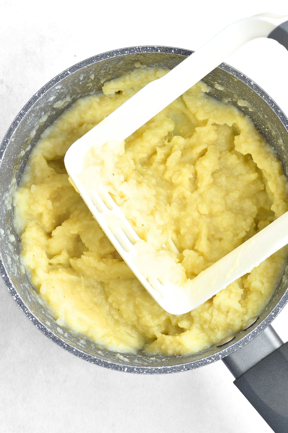 Using a masher to mash potatoes and cauliflower