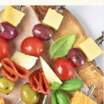 Top down view of antipasto kabobs on wooden board.