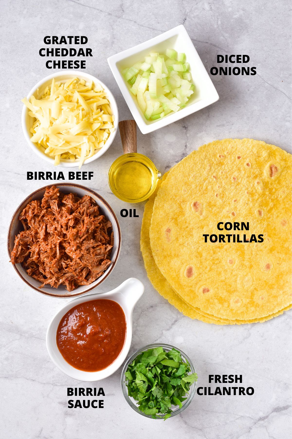 Ingredients for cheesy birria tacos recipe laid out on marble board.