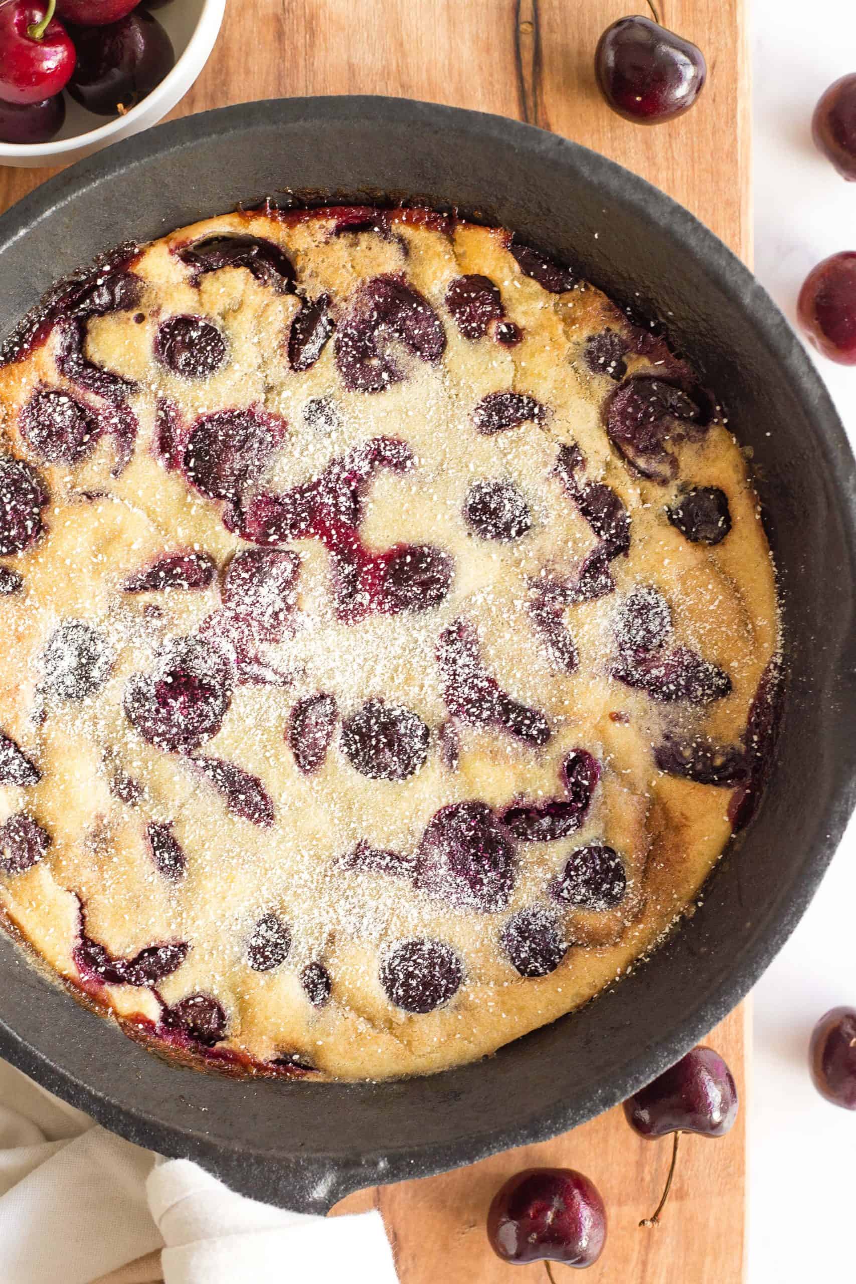 Clafoutis dessert in pan on wooden board.