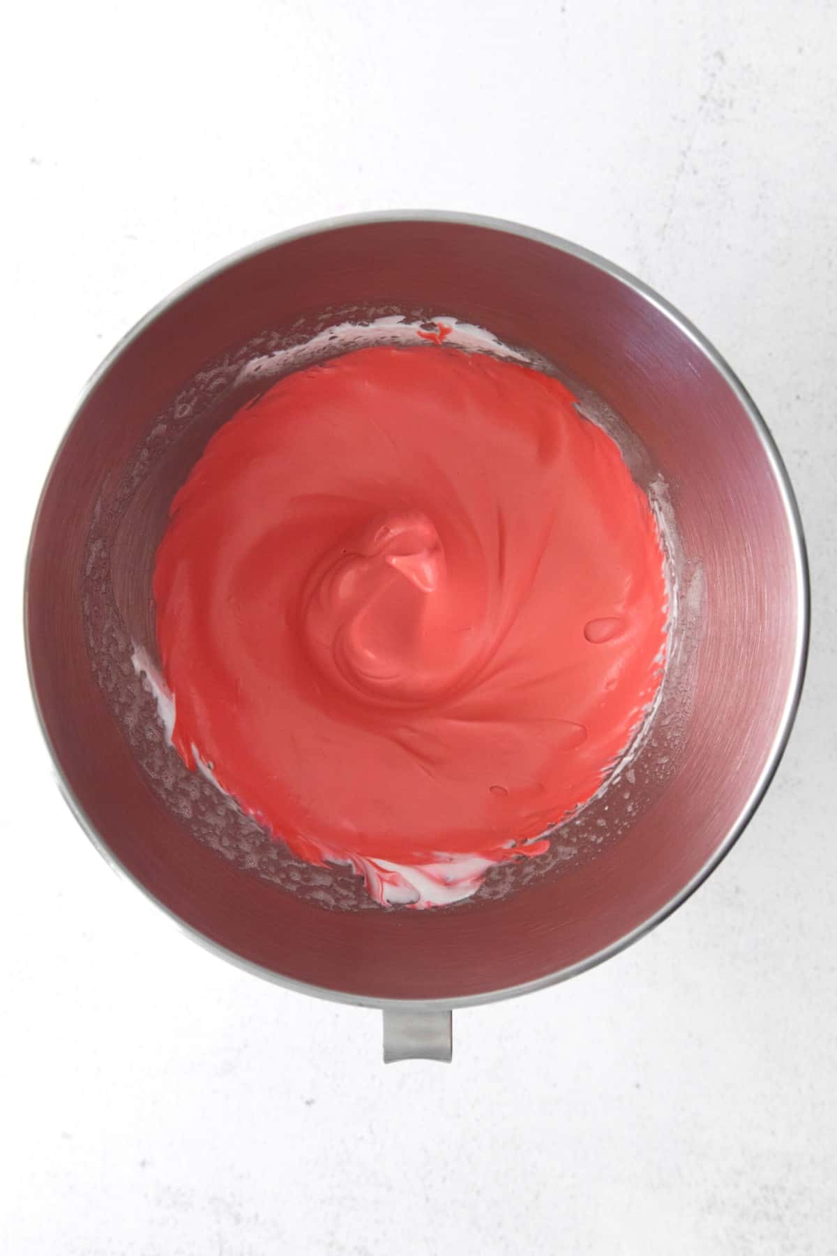 Red macaron batter in a metal bowl.