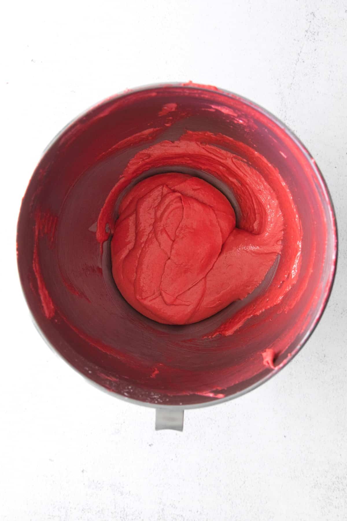 Red batter in a large metal bowl.