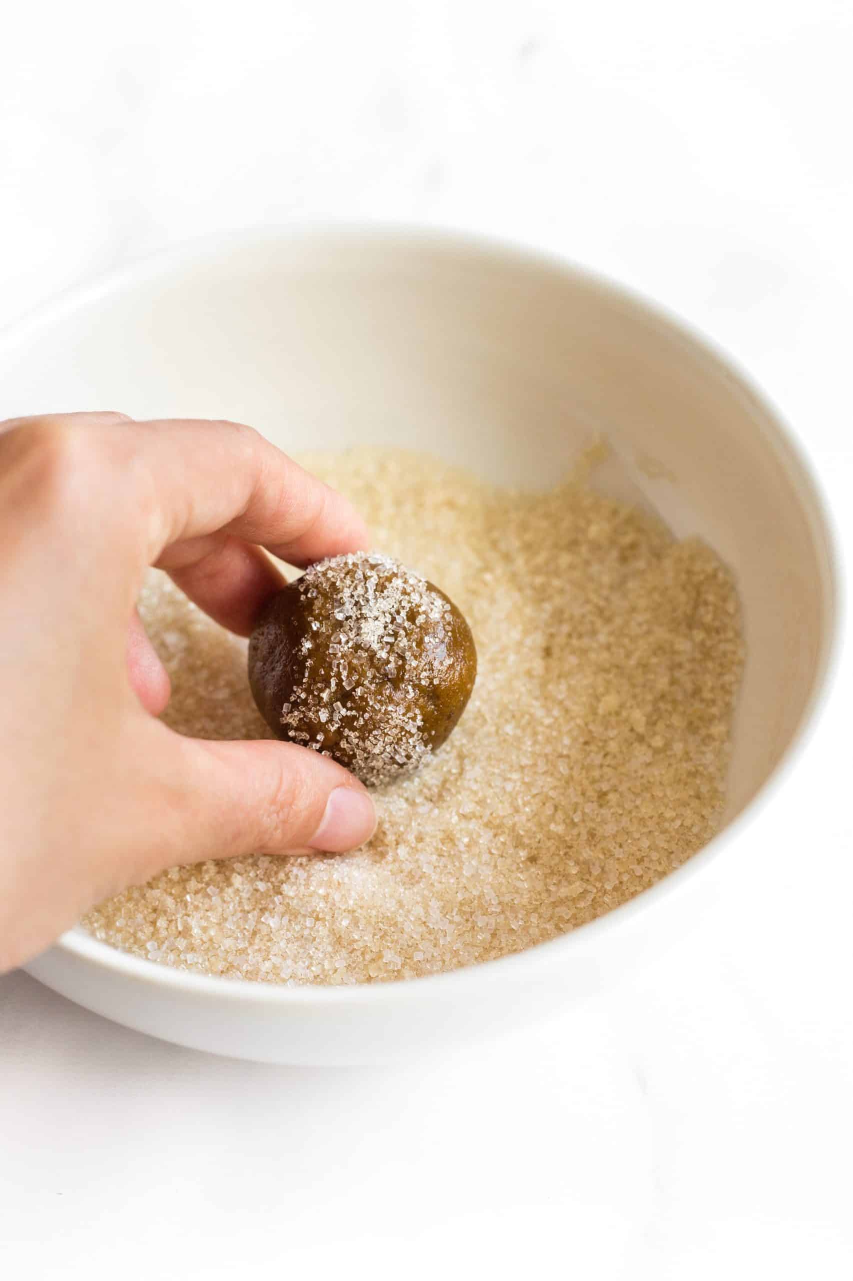 Rolling a cookie dough ball in sugar.