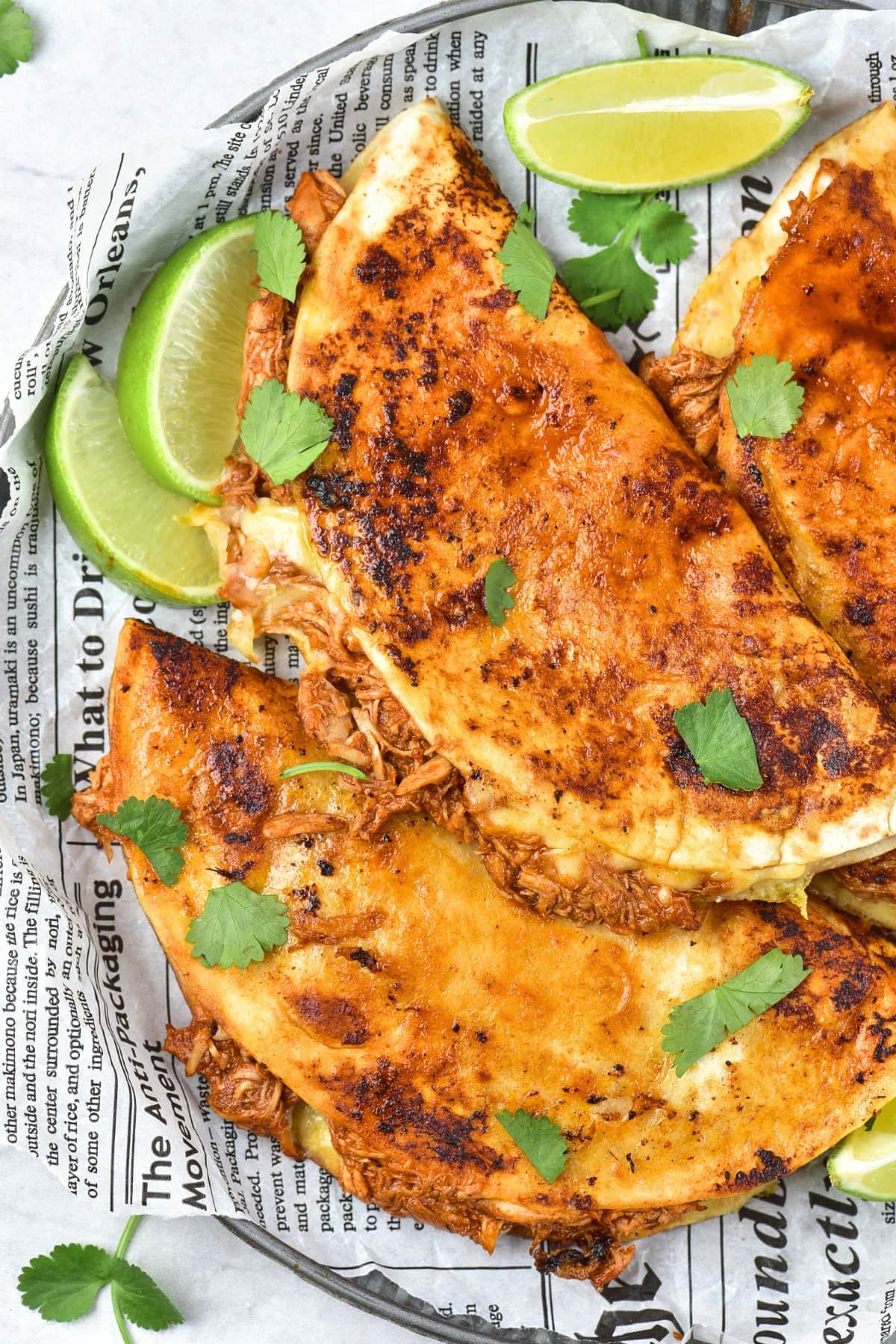 Tacos and lime wedges on parchment paper-lined plate.