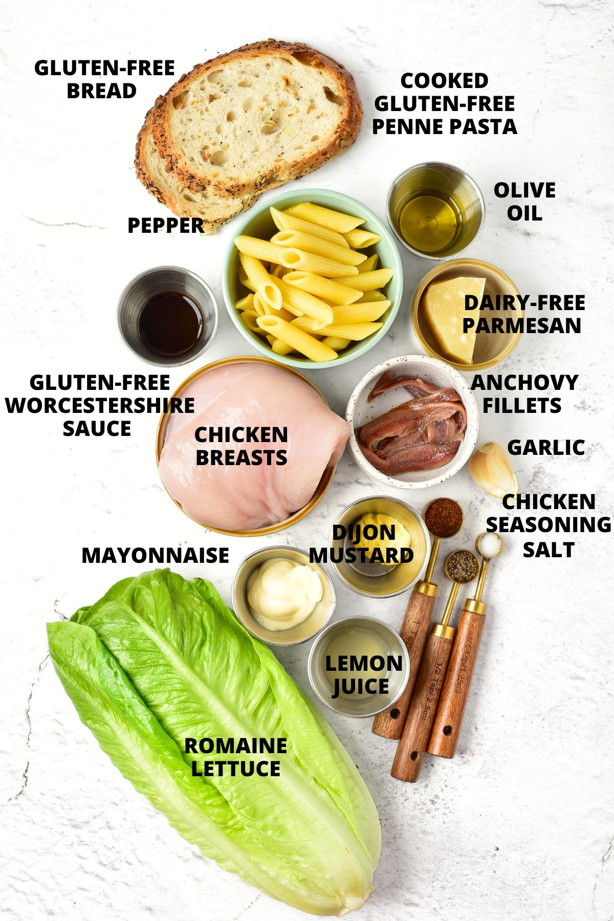 Ingredients for chicken caesar pasta salad recipe laid out on marble board.