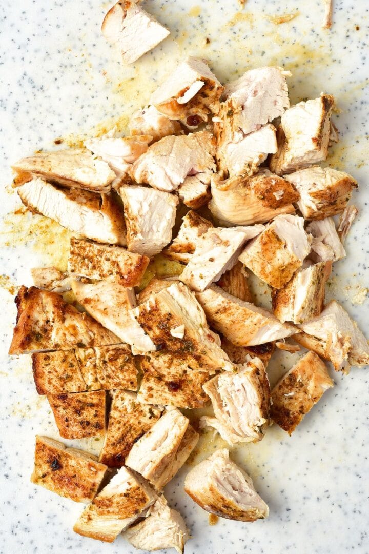 Cut cooked chicken on chopping board.