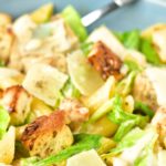 Up close view of a bowl of chicken pasta caesar salad