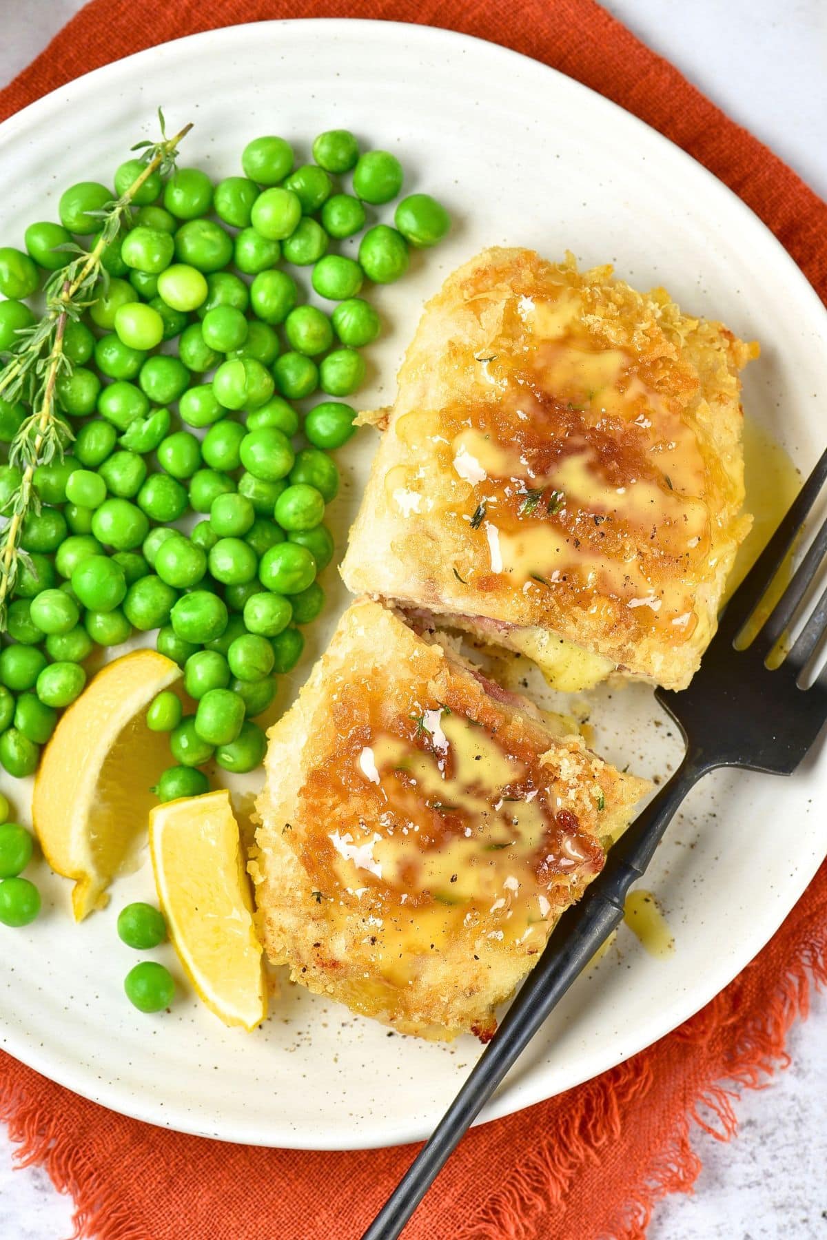 Top down view of gluten-free chicken cordon bleu, peas and fork on a plate