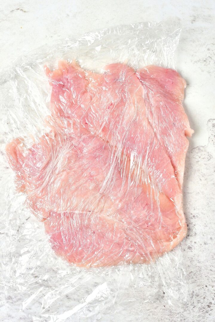 Pounded chicken breast fillets in plastic wrap