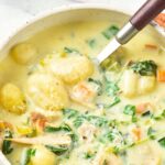 Holding up a spoonful of gnocchi from a bowl of soup.