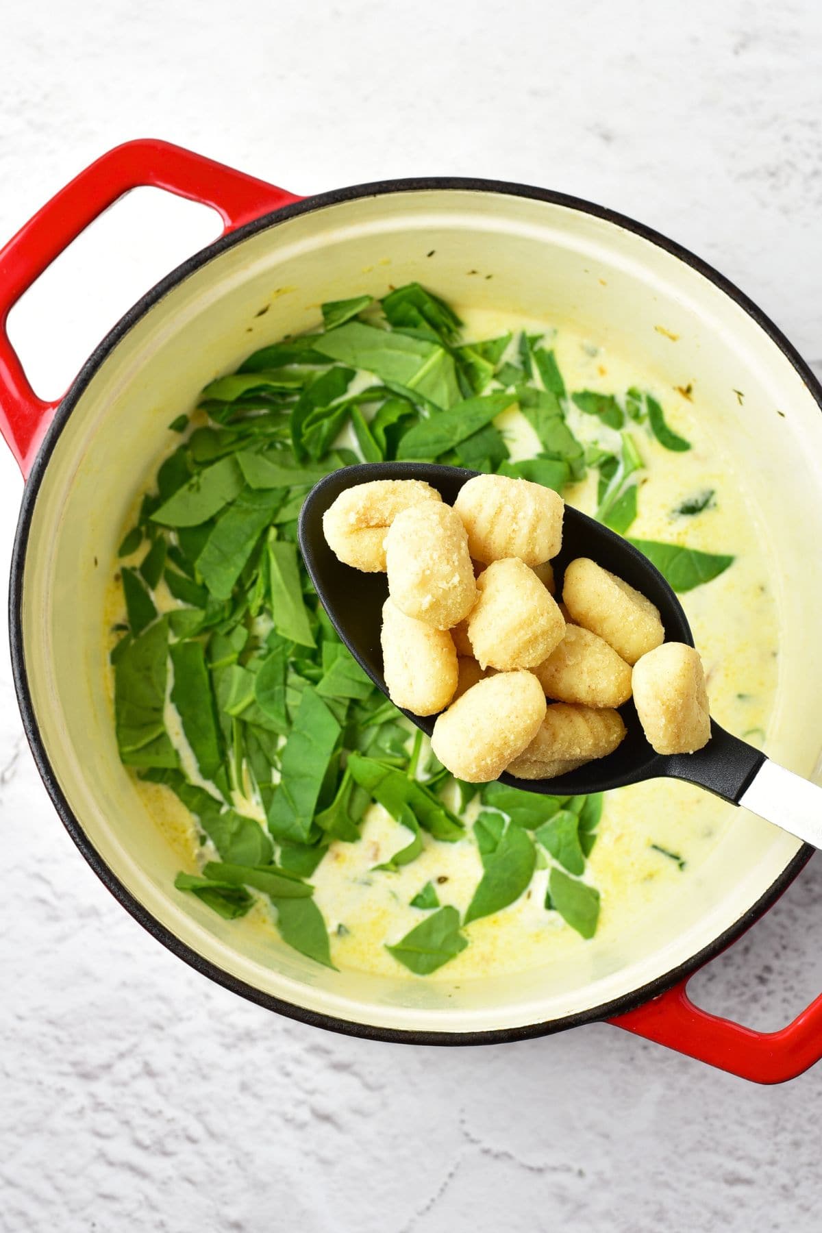 Holding a ladle of gluten-free gnocchi on top of soup