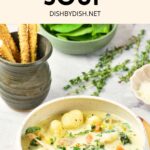 A bowl of chicken gnocchi soup on wooden board.