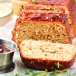 Sliced chicken meatloaf and a bowl of glaze