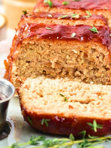 Sliced chicken meatloaf and a bowl of glaze