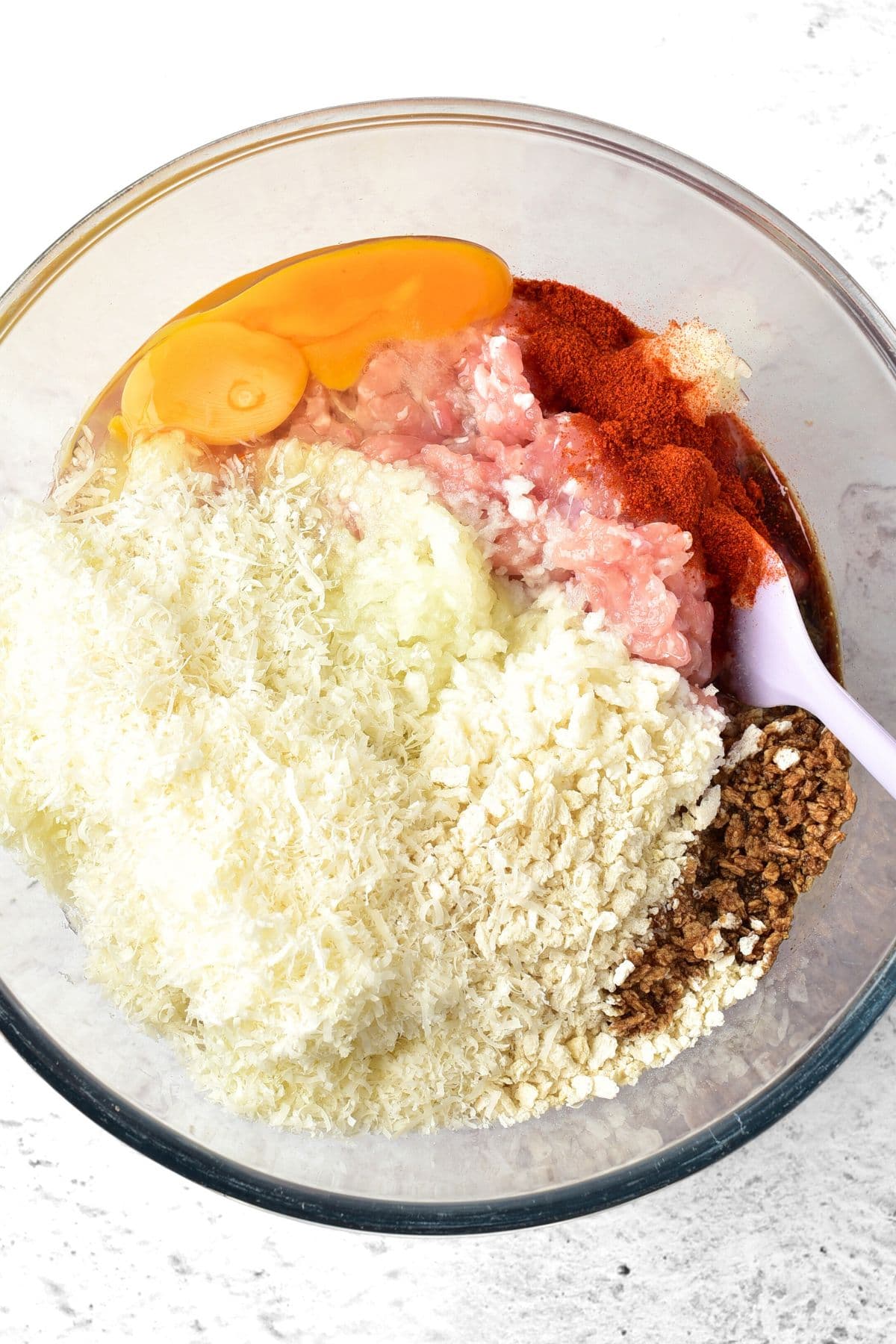 Parmesan cheese, panko breadcrumbs, eggs, ground chicken and spices in bowl.
