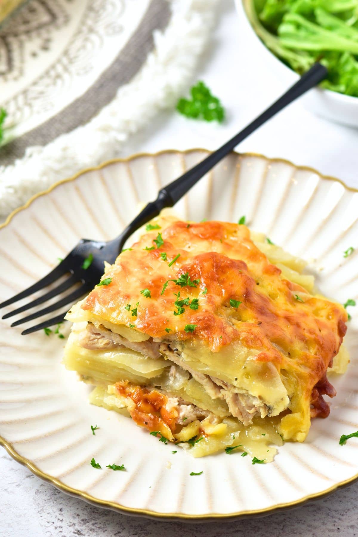 A plate of chicken and potato casserole with a fork